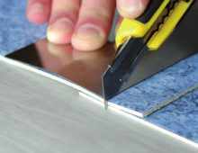 Разрежьте полосы напольного покрытия, уложенные внахлест (3–5 см), с помощью ножа и металлической линейки/планки (метод резки внахлест)