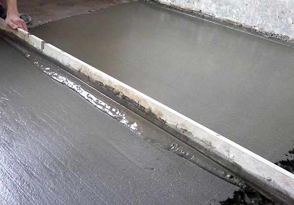 Равнение правилом бетонной стяжки